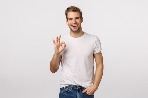 Hübscher blonder Kerl mit den blauen Augen, die Zustimmungszeichen geben