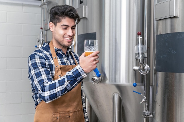 Hübscher Brauer im Vorfeld, der Bier in der Brauerei testet