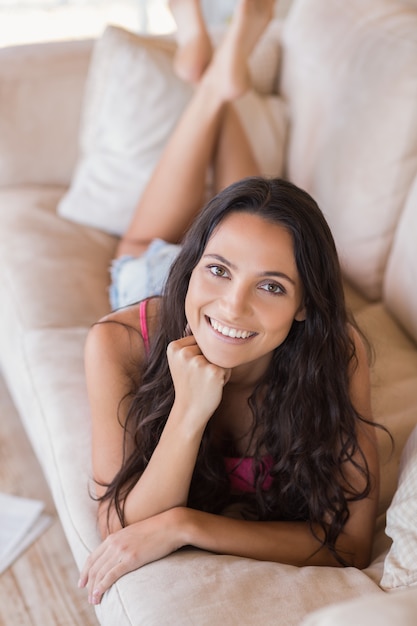 Hübscher Brunette, der auf der Couch sich entspannt