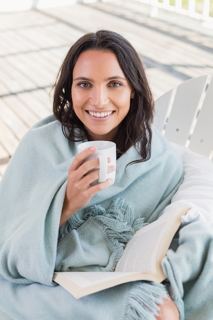 Hübscher Brunette, der auf einem Stuhl sitzt und Kaffee trinkt