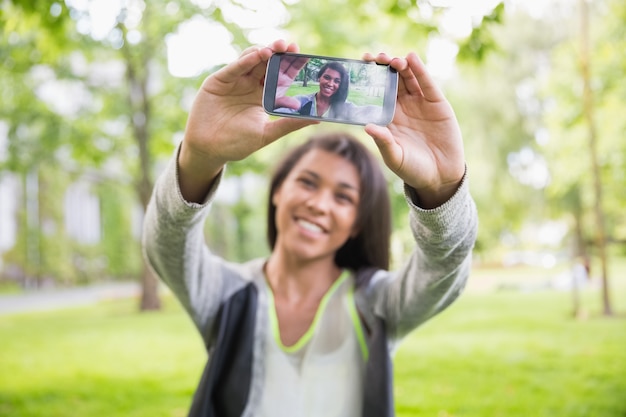 Hübscher Brunette, der ein selfie im Park nimmt