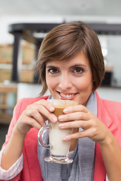 Hübscher Brunette, der ihren Latte genießt