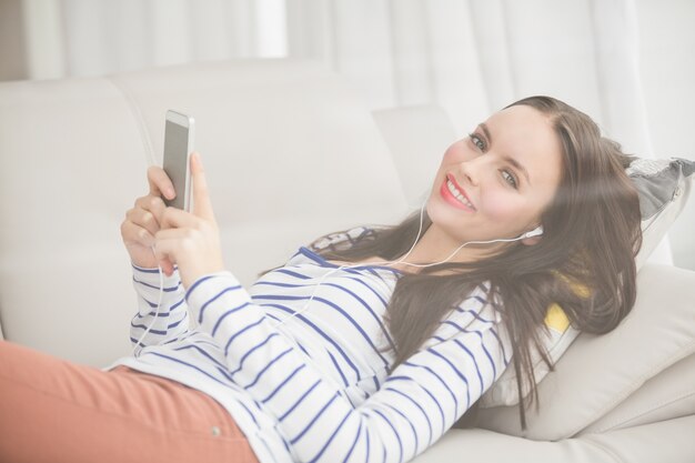 Hübscher Brunette, der Musik auf der Couch hört