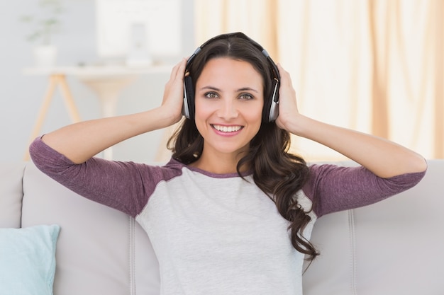 Hübscher Brunette, der Musik auf der Couch hört