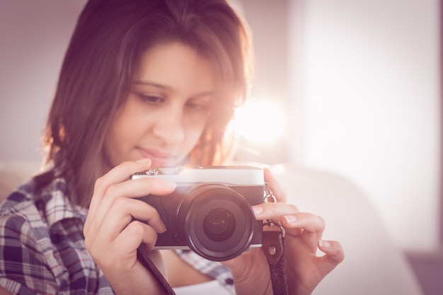 Hübscher Brunette, der Retro- Kamera auf Couch betrachtet