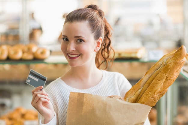 Hübscher Brunette mit Tasche des Brotes und der Kreditkarte