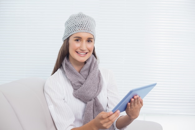 Hübscher Brunette mit Winterhut auf dem Halten der Tablette