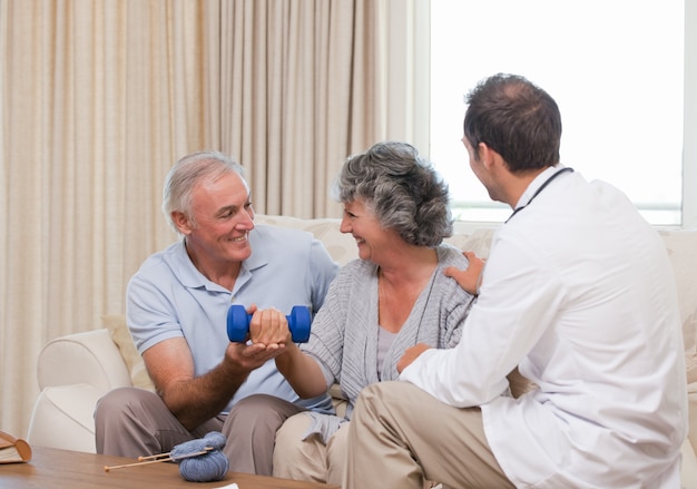 Hübscher Doktor, der seinem Patienten hilft, Übungen zu tun