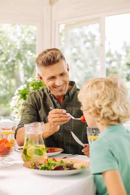 Foto hübscher ehemann, der seinem sohn etwas tomate gibt