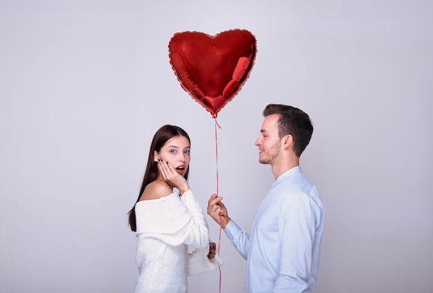 Hübscher eleganter Kerl gibt einer Frau einen Ballon.