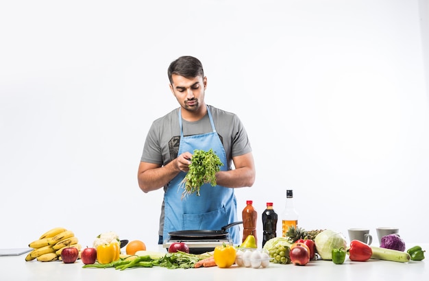 Hübscher, fröhlicher, lächelnder indischer Mann, der Essen in der Küche zubereitet, gesundes Essen, Kochkonzept.