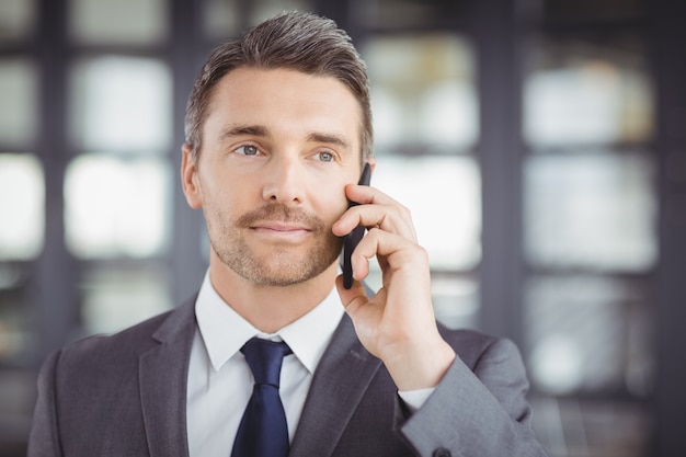 Hübscher Geschäftsmann, der auf Mobiltelefon spricht