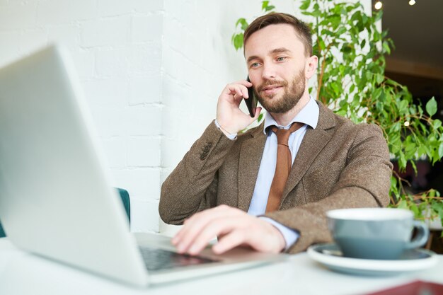 Hübscher Geschäftsmann, der durch Telefon spricht