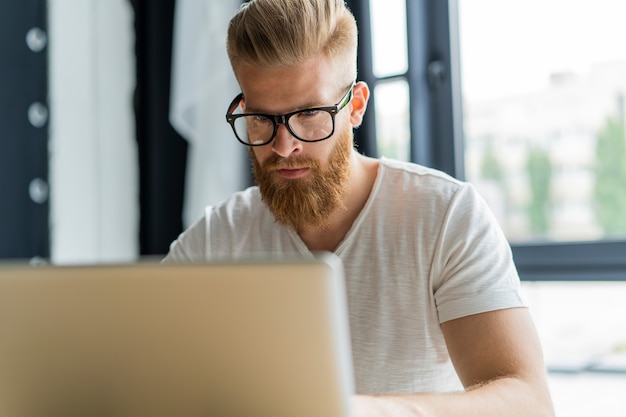 Hübscher Geschäftsmann, der mit Laptop im Büro arbeitet.