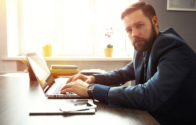 Hübscher Geschäftsmann, der mit Laptop im Büro arbeitet.