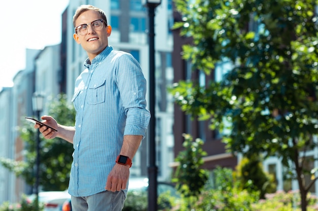 Hübscher Geschäftsmann, der Smartphone hält, während er draußen steht