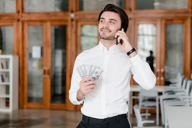 Hübscher Geschäftsmann mit Geld im Büro