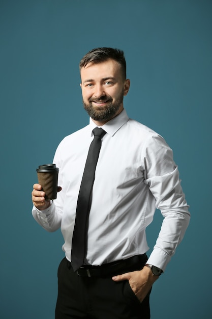 Hübscher Geschäftsmann mit Tasse Kaffee auf Farbe