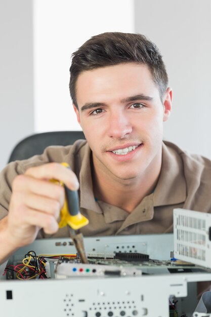 Hübscher glücklicher Computeringenieur, der offenen Computer repariert