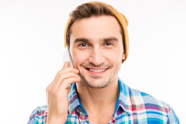 Hübscher glücklicher Mann mit Hut, der am Telefon spricht