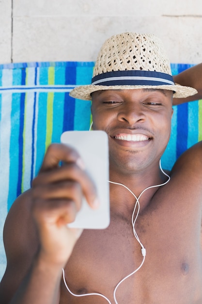 Hübscher hemdloser Mann, der Musik Poolside hört