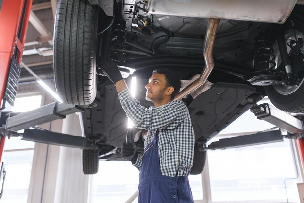 Hübscher indischer Automechaniker beim Autoservice