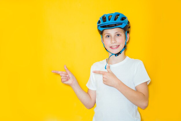 Hübscher jugendlicher Junge, der Radfahrersicherheitshelm über lokalisiertem gelbem Hintergrund trägt. Gewinnerkonzept