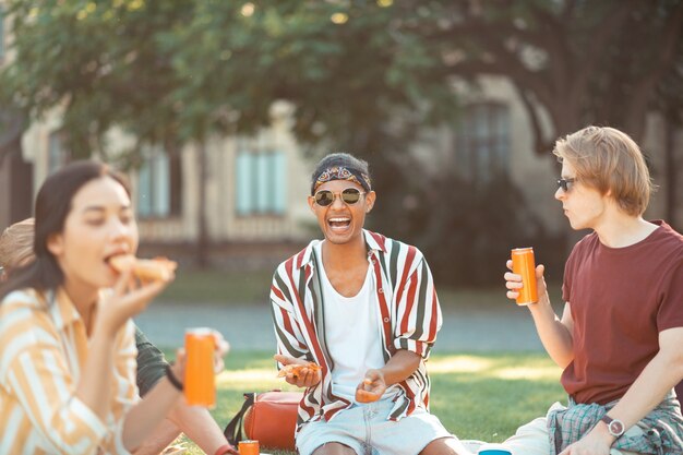 Hübscher Junge, der während des Picknicks mit seinen Universitätsfreunden lacht