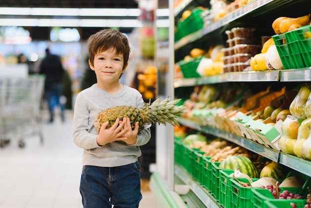 Hübscher Junge mit Ananas im Supermarkt