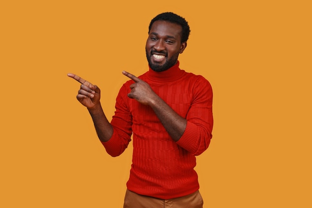 Hübscher junger afrikanischer Mann in Freizeitkleidung, der gestikuliert und lächelt