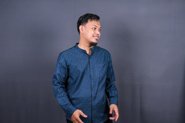 Hübscher junger asiatischer Mann auf grauem Hintergrund. Moslem, Indonesien