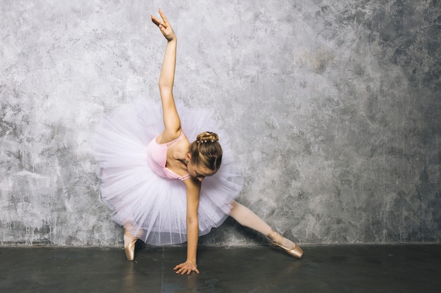 Hübscher junger Ballerina-Tänzer, der klassisches Ballett gegen rustikale Wand tanzt