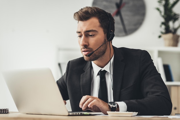 Hübscher junger Call-Center-Arbeiter mit Laptop