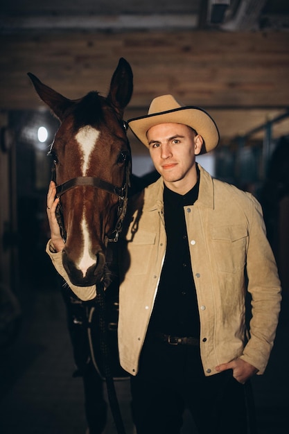 Hübscher junger Cowboy auf einer Ranch mit einem Pferd