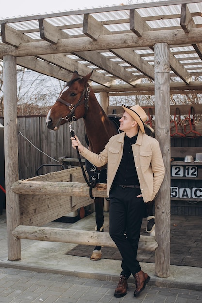 Hübscher junger Cowboy auf einer Ranch mit einem Pferd