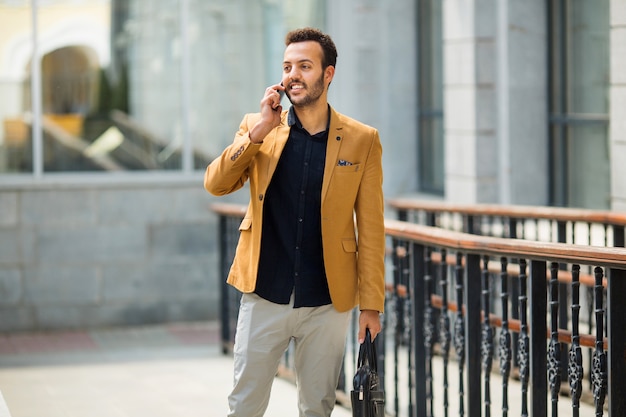 hübscher junger erwachsener Mann in einem Anzug, der mit einer Handbewegung am Telefon spricht