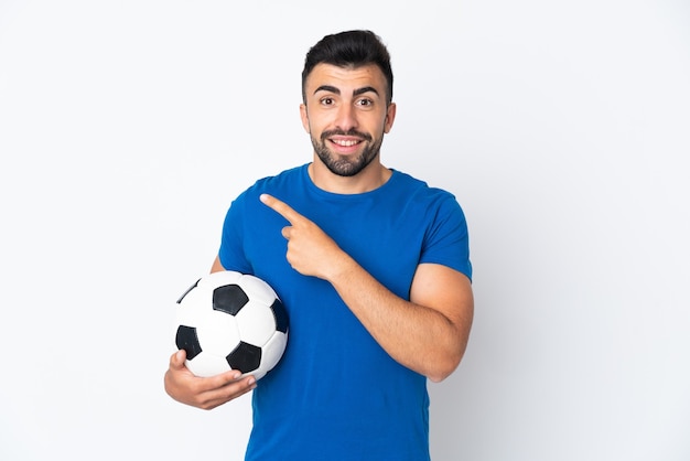 Hübscher junger Fußballspieler Mann über isolierter Wand, die zur Seite zeigt, um ein Produkt zu präsentieren