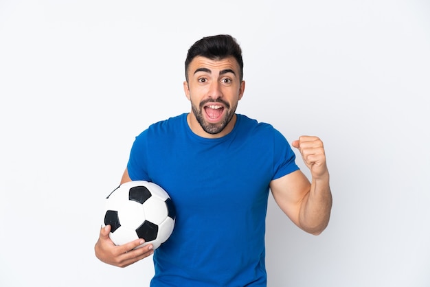Hübscher junger Fußballspieler Mann über Mauer, der einen Sieg in der Siegerposition feiert