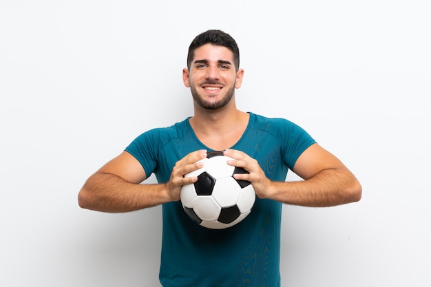 Hübscher junger Fußballspielermann über lokalisierter weißer Wand