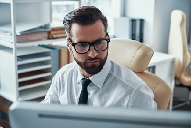 Hübscher junger Geschäftsmann, der am Schreibtisch arbeitet