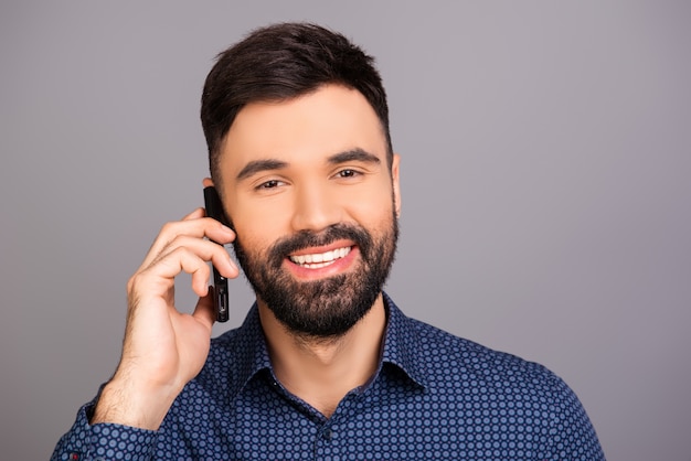 Hübscher junger Geschäftsmann, der auf seinem Smartphone spricht