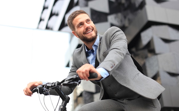 Hübscher junger Geschäftsmann, der draußen Fahrrad in der Stadt fährt