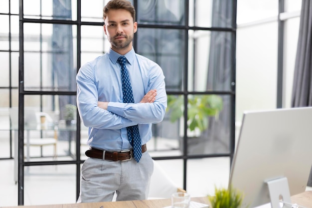 Hübscher junger Geschäftsmann, der im modernen Büro steht