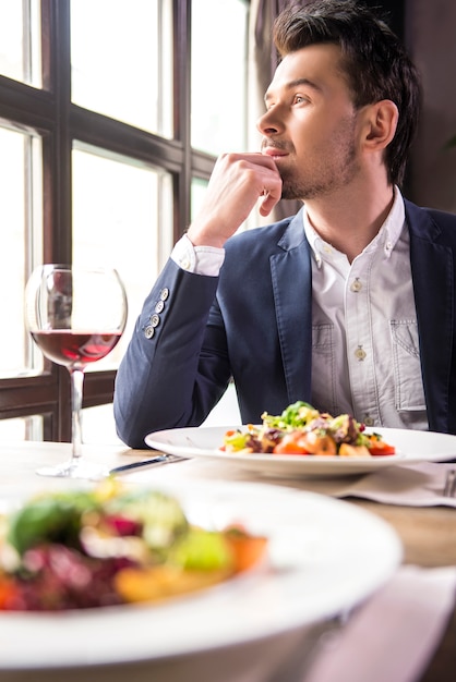 Hübscher junger Geschäftsmann, der während eines Business-Lunchs isst.