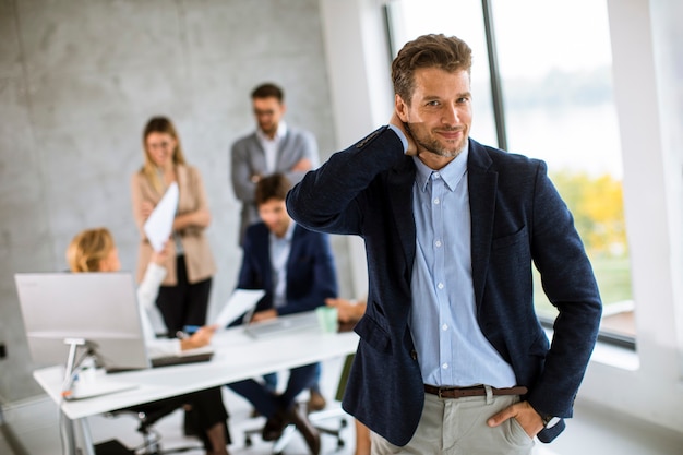 Hübscher junger Geschäftsmann, der zuversichtlich im Büro vor seinem Team steht