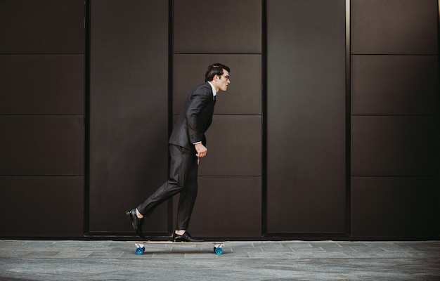 Hübscher junger Geschäftsmann mit seinem modernen Longboard