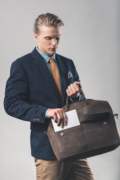 Hübscher junger Geschäftsmann mit stilvoller Aktentasche aus Leder und Tablet
