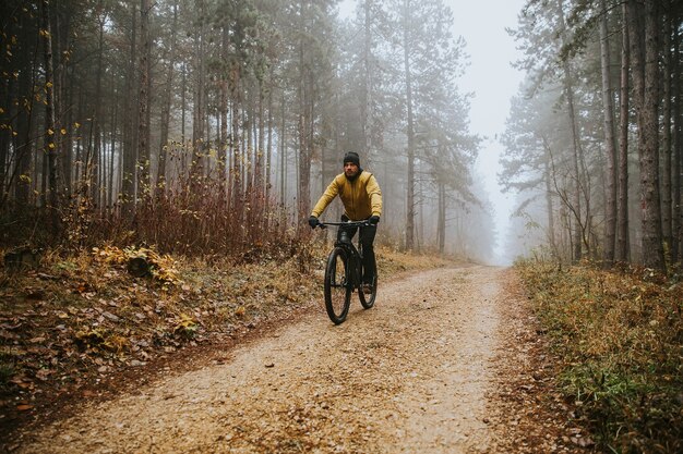 Hübscher junger Mann, der durch Herbstwald radelt