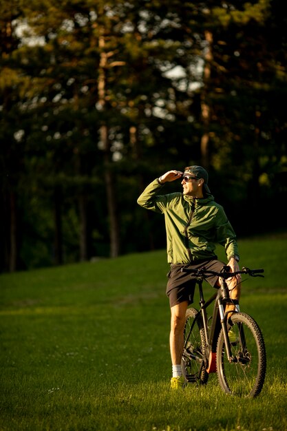 Hübscher junger Mann, der E-Bike im Park reitet