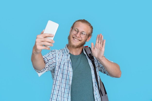 Hübscher junger Mann, der ein Selfie macht und mit der Hand winkt